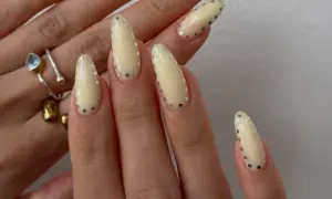 Modne paznokcie w jasnych kolorach, ozdobione srebrnymi kropkami. Delikatny, pastelowy manicure z błyszczącymi detalami.