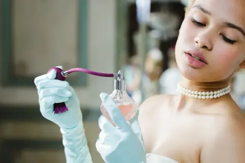 Elegancka kobieta w rękawiczkach aplikuje perfumy. Dowiedz się, jak sprawdzić oryginalność perfum, by cieszyć się pięknym zapachem.