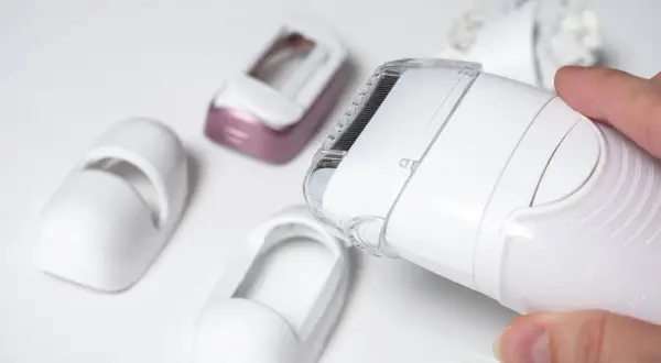 Dłoń trzyma depilator Philips Lumea, obok leżą różne nasadki. Dowiedz się, jak używać Philips Lumea.